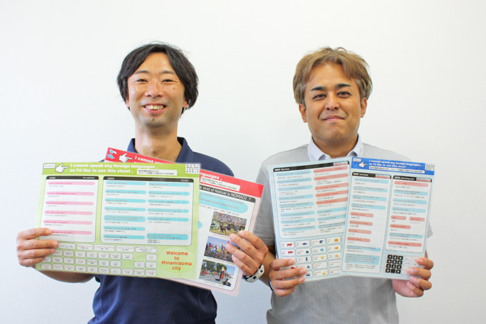 指差しコミュニケーションボードを持つ市職員の写真