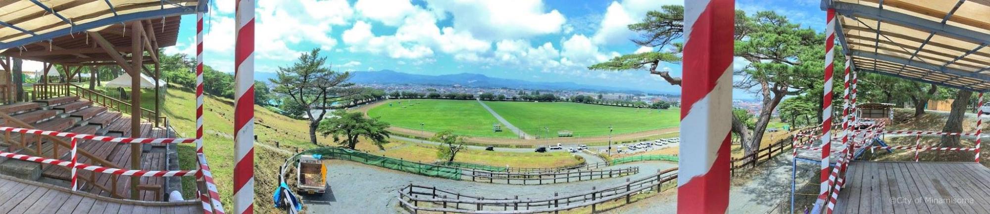 山頂から原っぱを見下ろす写真
