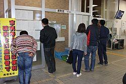 南相馬市市役所に貼り付けられている安否確認掲示板を確認しにきてる人々の写真