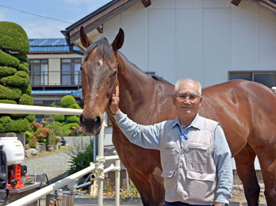 自宅の前で馬の顔をなでる男性と馬の画像