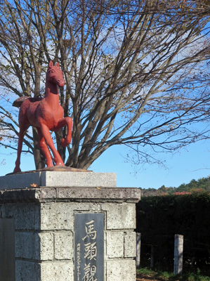 馬頭観世音の銘板の上に、れんが色の馬の像が見える画像