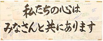 「私たちの心はみなさんと共にあります」の大きな文字の周りに記入された応援メッセージの写真
