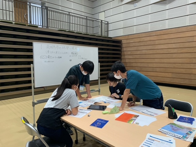 学生らが机を囲んでワークショップをしている様子の写真