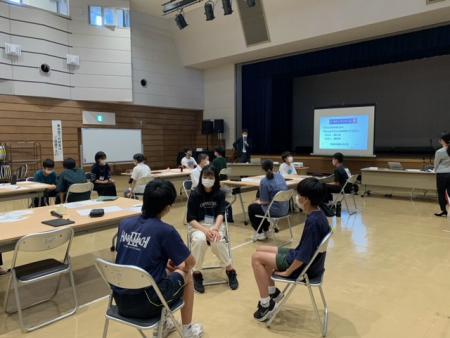 学生3人が椅子に座り向かい合ってワークショップを行っている様子の写真