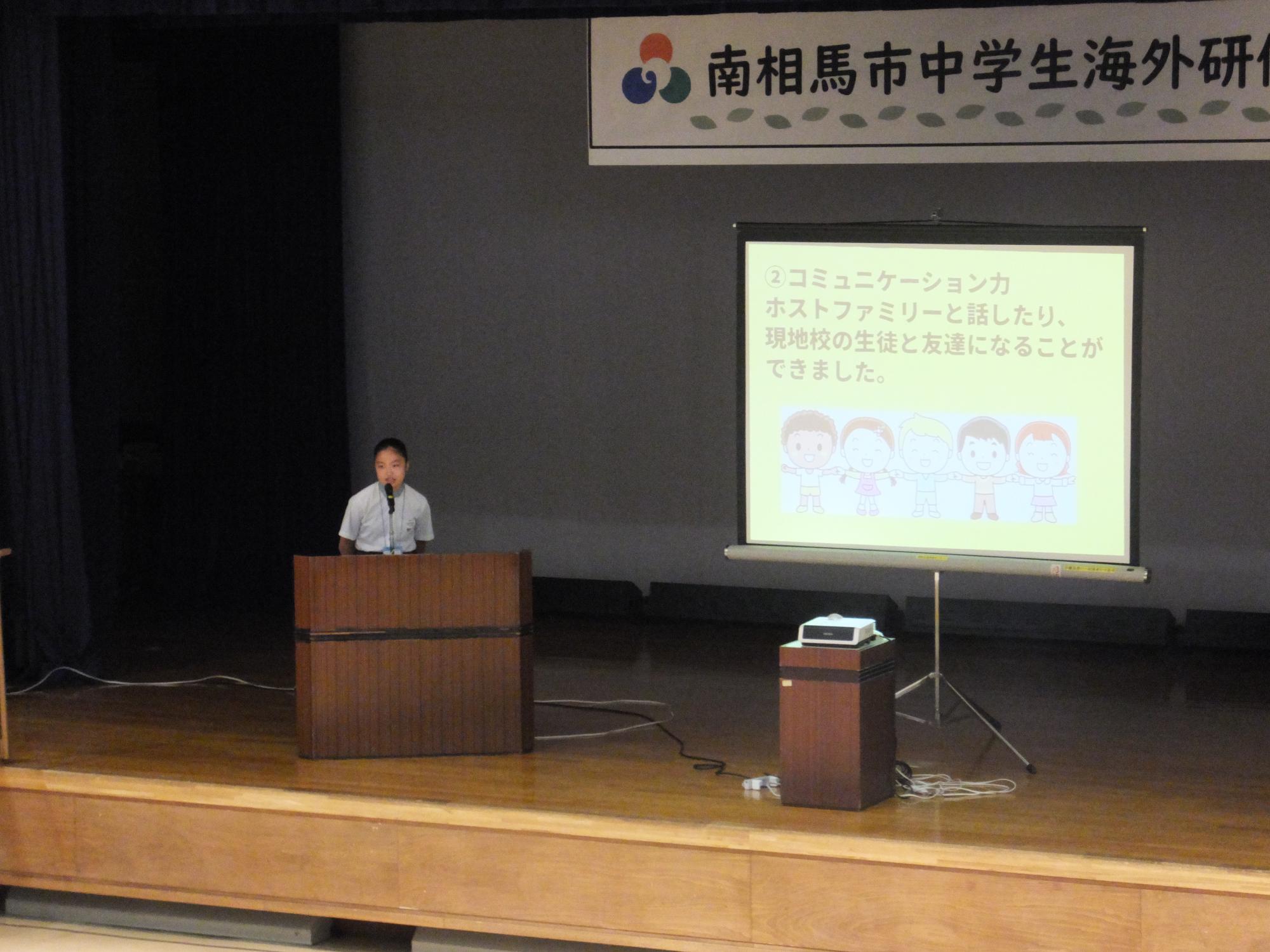 報告会でプレゼンテーションを行っている様子の写真