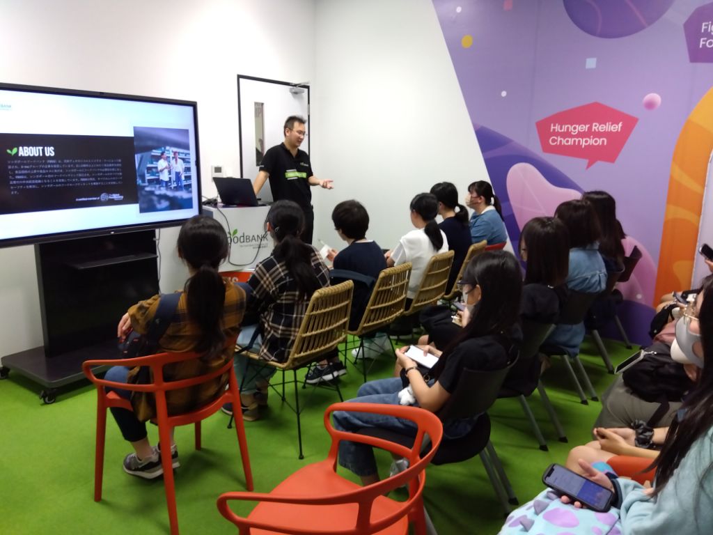 フードバンクで説明を受けている学生らの写真