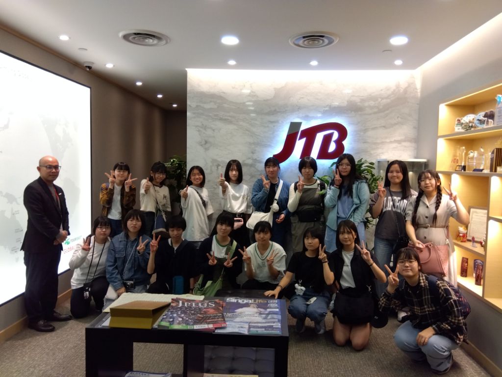壁にJTBと書かれた前での現地企業訪問の集合写真
