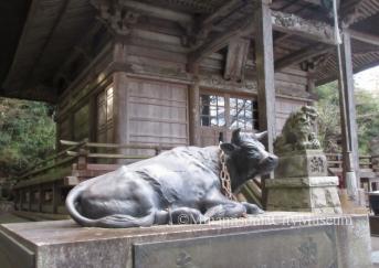 寺のお堂の前に右向きに寝そべる石造りの牛の像がある