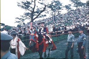 メンコ(覆面)をつけた馬に乗って野馬追に出ている子どもの騎馬武者