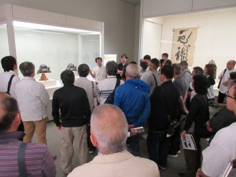 展示室の甲冑を解説する講師とそれを聞く受講者たち