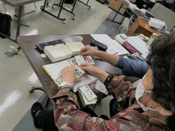 手書きのカルタの絵札と読み札を手にする女性