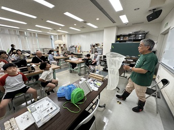 昆虫観察について解説する講師とそれを聞く受講者たち