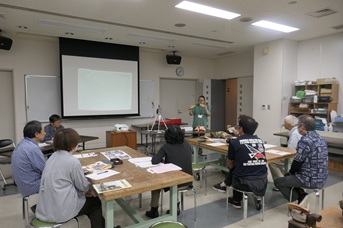 スクリーンに写真を映して発表する参加者とそれを聞く受講者たち