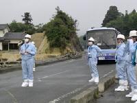 現地調査を行う水色の作業着を着た作業員達の写真