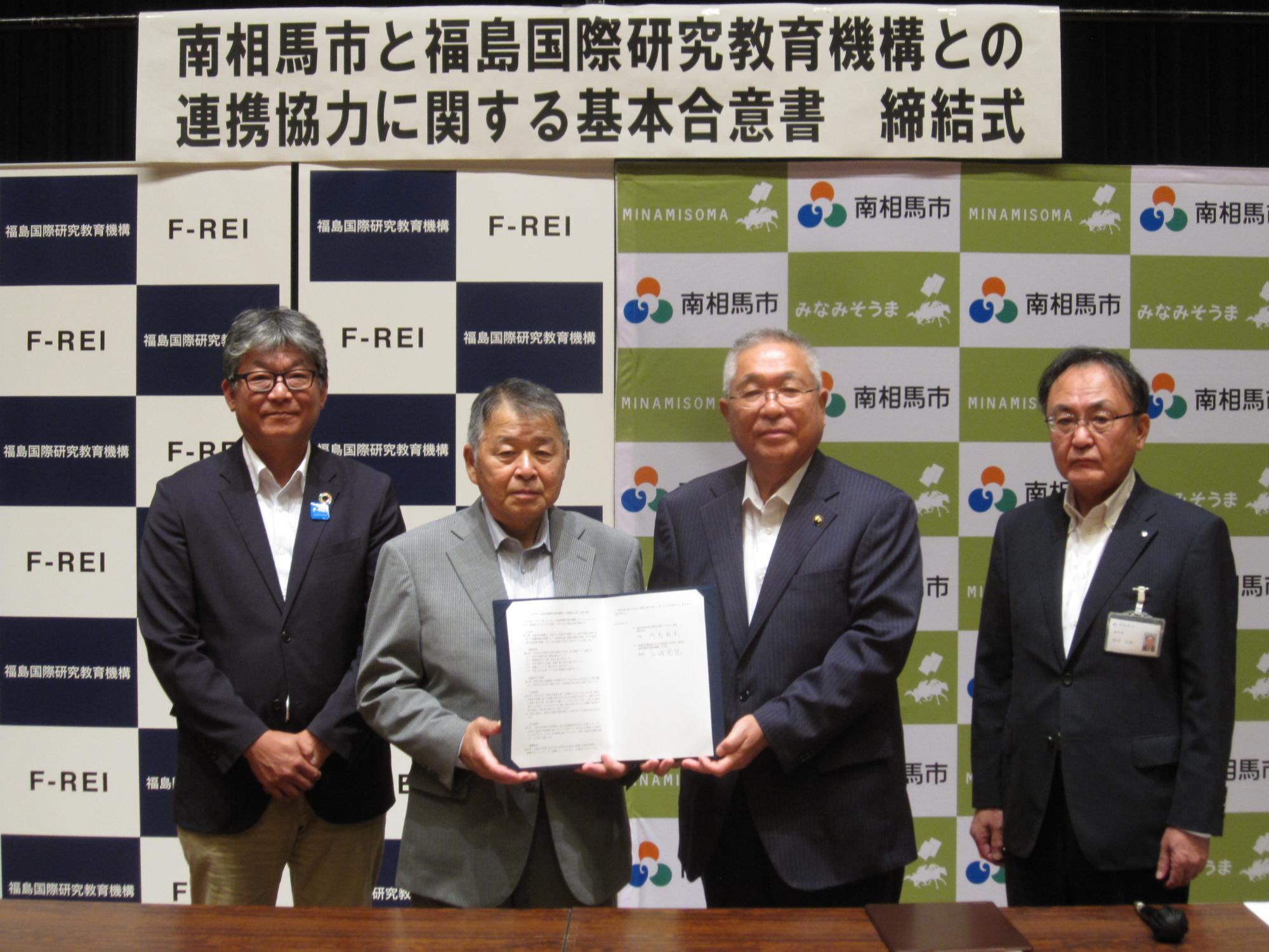 基本合意書を掲げている市長らの写真