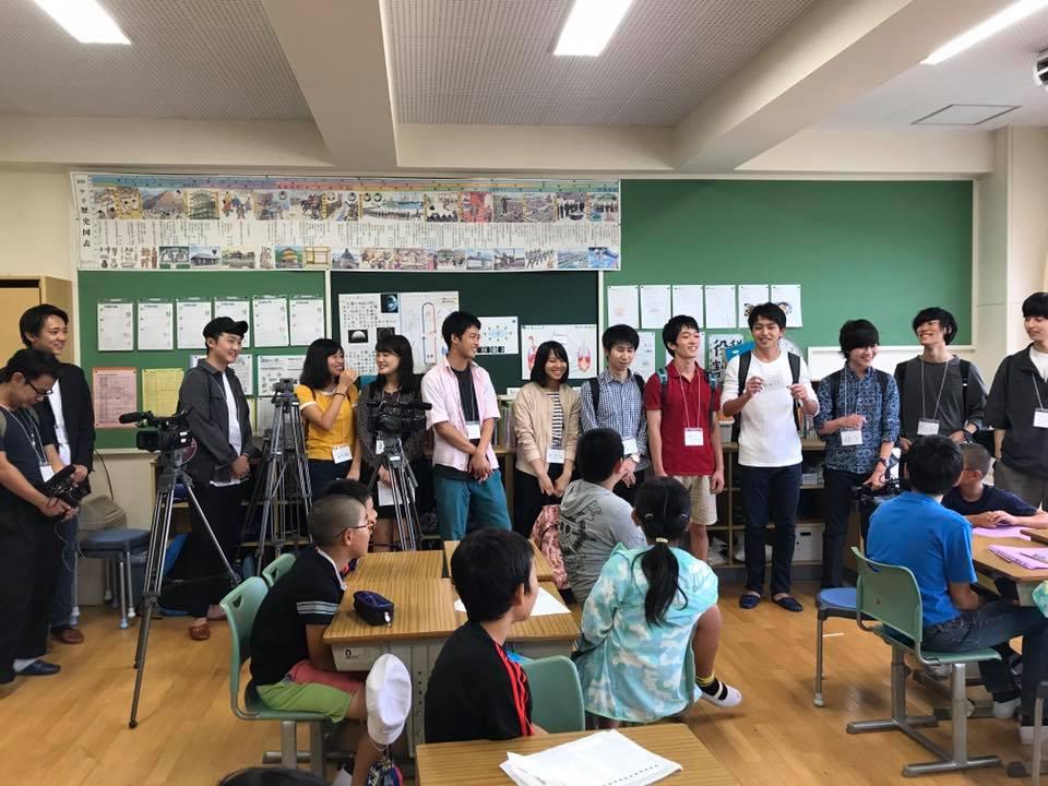 小学生と大学生が企画について説明している様子の写真