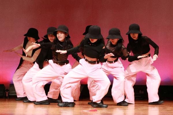 1黒いシャツと帽子、ピンク色のズボンを着て踊っている女子団体の写真