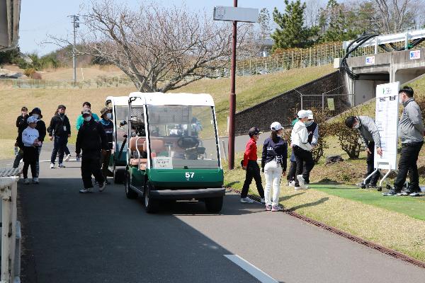 2ゴルフ場でスコアボードを見る選手たちとカートの写真