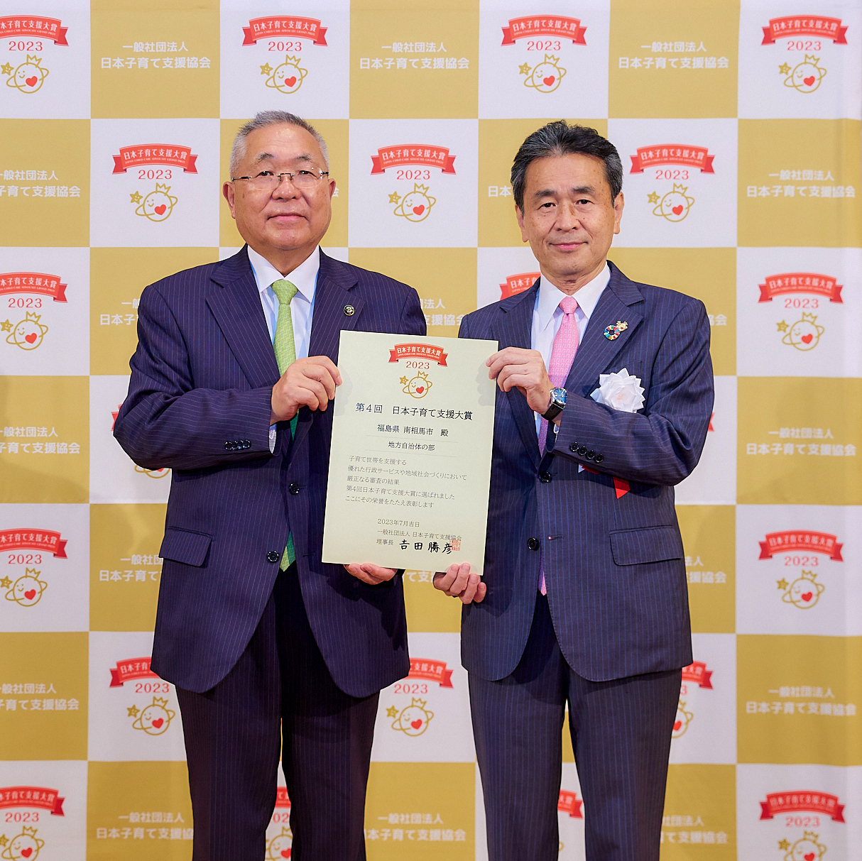 賞状を持ち記念撮影を受ける市長と日本子育て支援協会理事長の写真