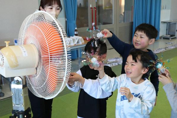 4ペットボトルから作ったプロペラを扇風機の風で回す子どもたちの写真