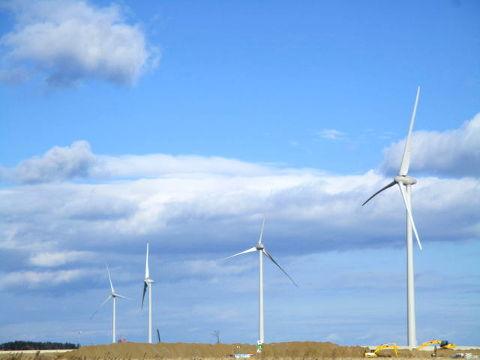 青空の中4基の風力発電機が稼働している写真