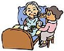 寝たきりの高齢者女性と食事を与えている女性の画像