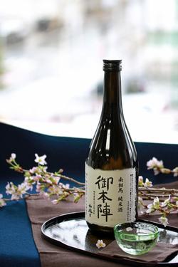 地酒御本陣が注がれたグラスと瓶の奥に桜の花が添えられ、綺麗にディスプレイされた写真