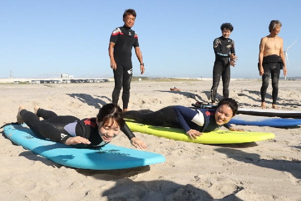 砂浜でサーフボードに乗る参加者の写真