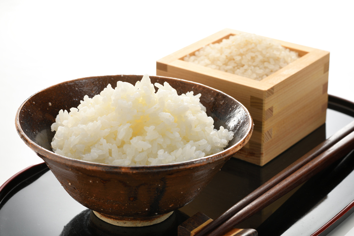 陶器の茶碗に盛られた白米と升に入った生米の写真