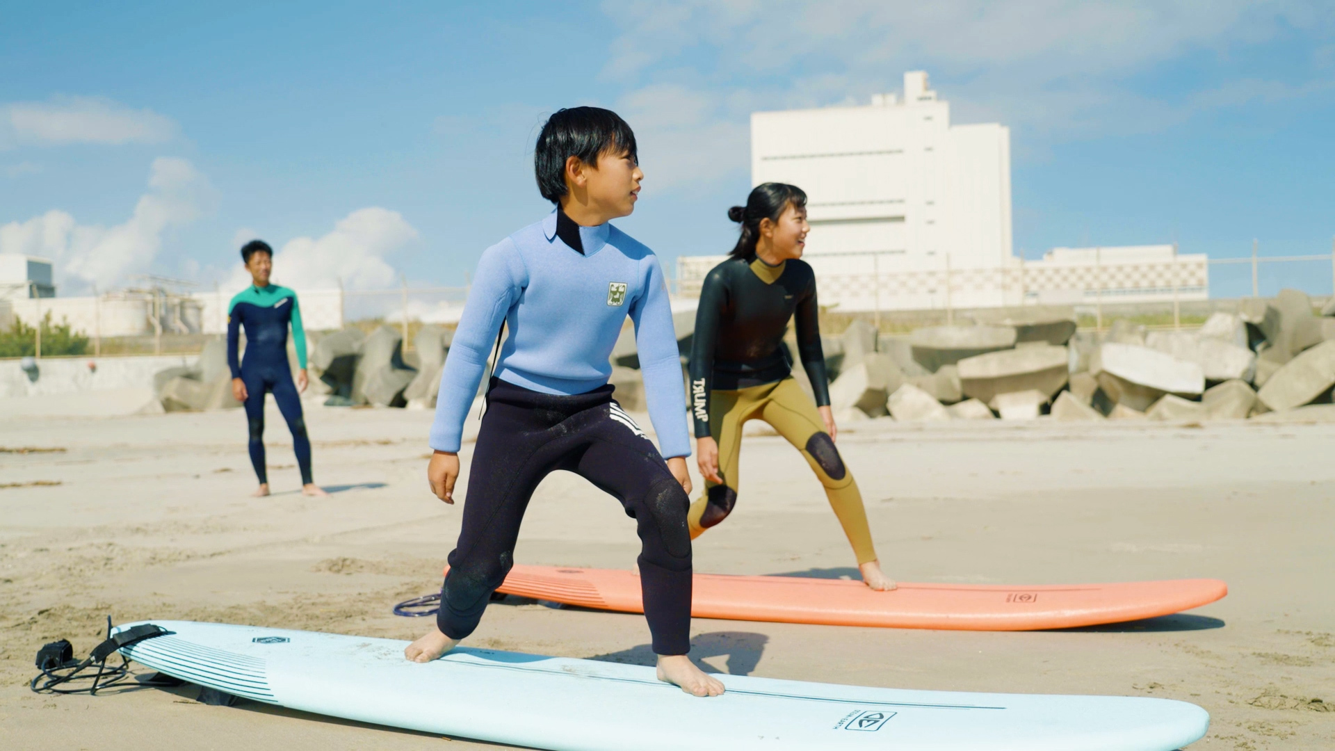 砂浜でサーフボードに乗る子どもの写真