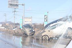 津波の海水も引いていない国道6号線の道路脇に流木と複数の車両の写真