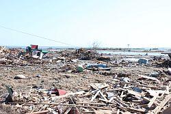 住宅があっただろう場所に津波が押し寄せ、全てを攫い瓦礫だけが残されている写真