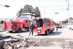 津波の影響で陥没した道路を復旧作業する複数の消防団と消防団員の写真