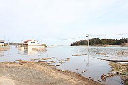 震災から3日目だが未だに海水が引いておらず写真奥の二階建て家屋も一階部分が未だ漬かっている状態の写真