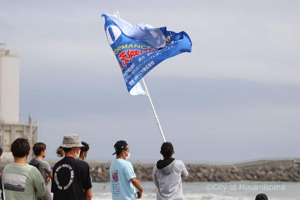 海に向かって応援旗を掲げる観覧者の写真