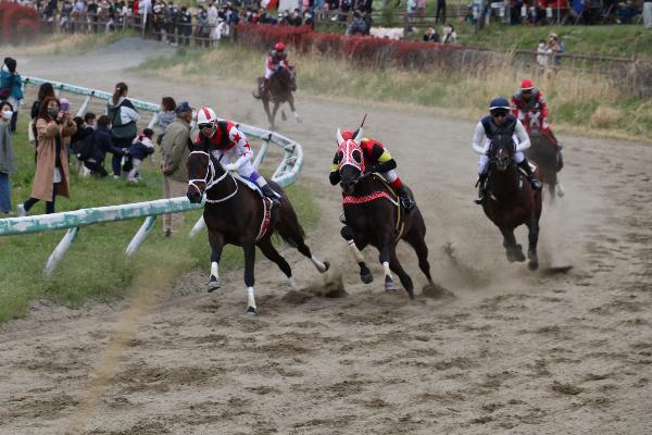 騎手を乗せた2頭の馬がコーナーを競り合いながら疾走している写真
