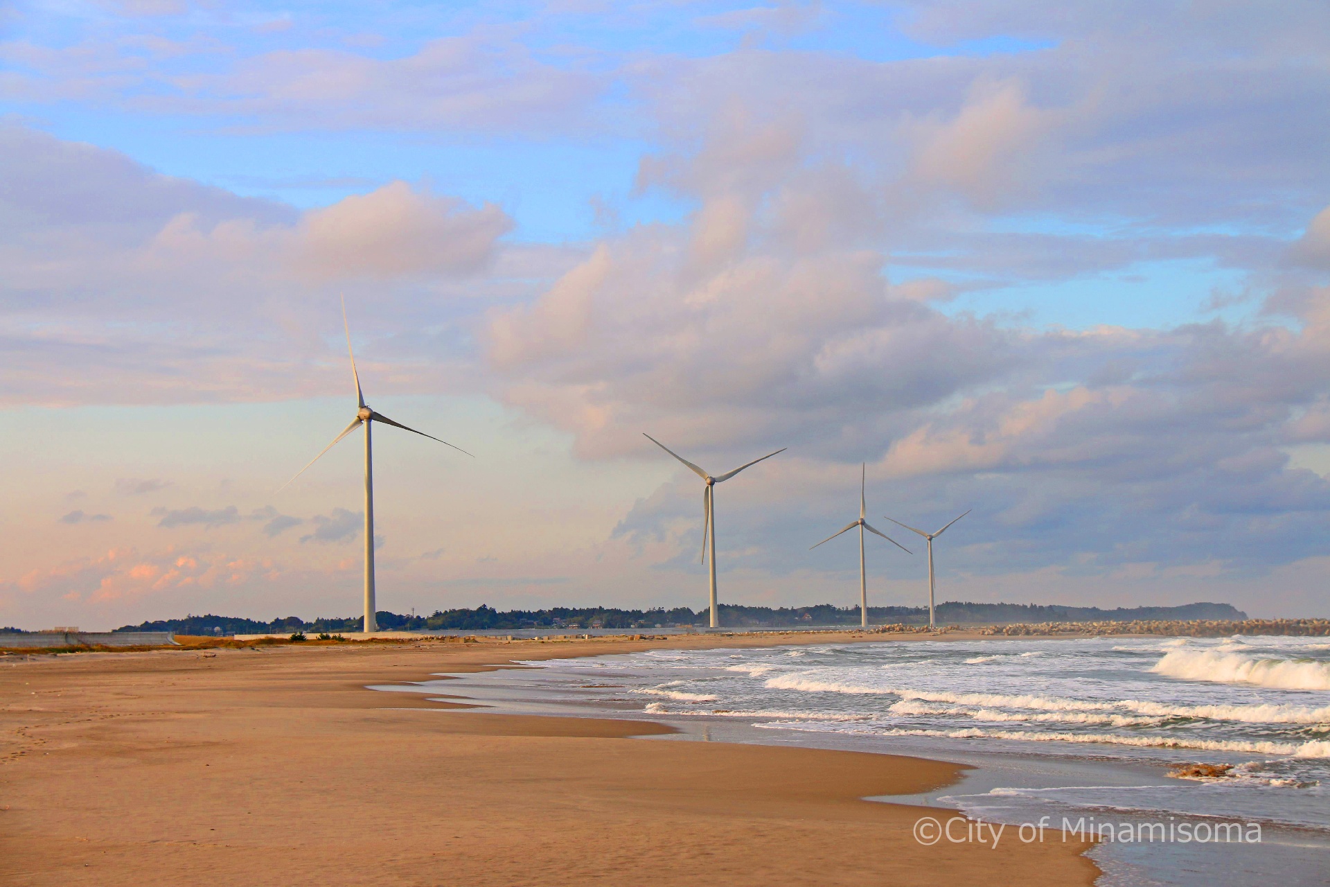 鹿島区北海老の海岸から北方を見る。風力発電の風車が回っている様子。