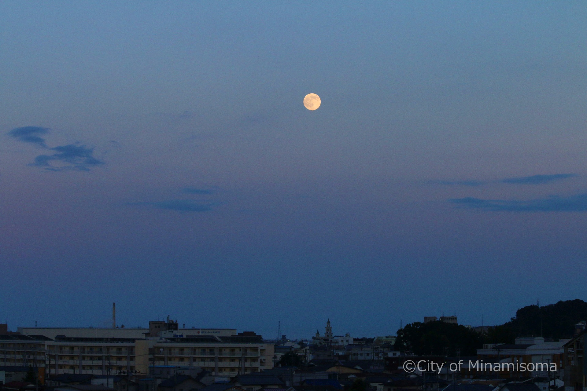 市役所の屋上から見た町の様子。薄青い夕暮れの空に、丸い月が浮かんでいる。