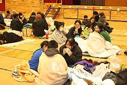 原町第一小学校に避難された方々が毛布にくるまって食べ物を食べたり、おしゃべりをしている写真