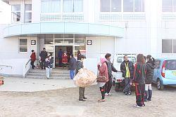 石神第一小学校に避難された方々が荷物を持ったり話をしている写真