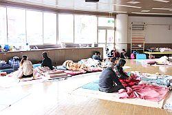 原町保健センターに避難された方々が敷物を敷いて座っている写真