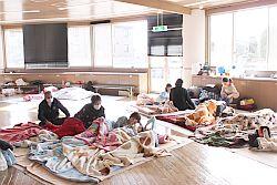 原町保健センターに避難された方々が敷物を敷いて寝たり、座ったりしている写真
