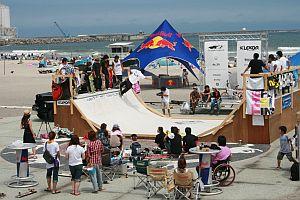 広い砂浜にハーフパイプ設備が設置されスケートボード大会が行われている写真