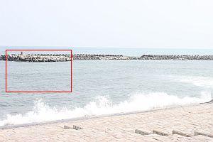 左奥のテトラポットがようやく顔を出している浜辺で手前にあった広い砂浜は波に覆われている写真（赤枠にて1枚前の写真の位置を示しています）