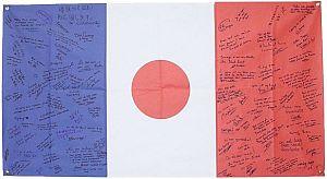 シオタノシイ協会から寄せられた日本とフランスの国旗を組み合わせた布に書かれた寄書きの写真