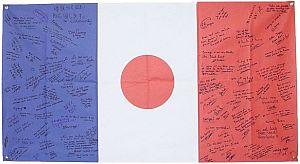 シオタノシイ協会から寄せられた日本とフランスの国旗を組み合わせた布に書かれた寄書きの写真