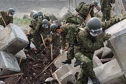 瓦礫の山を一つ手作業で掻き分け、行方不明者捜索をしている陸上自衛隊第一空挺団の人々の写真