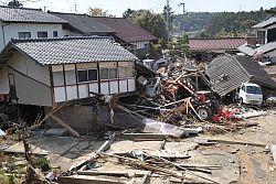津波で流されてきた建物や白い軽トラックが建物の下敷きになっている写真