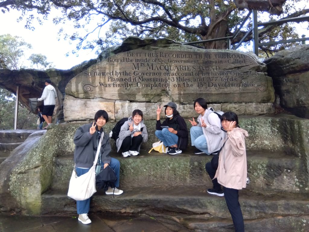 石で作られたベンチに座ってポーズする学生たちの写真