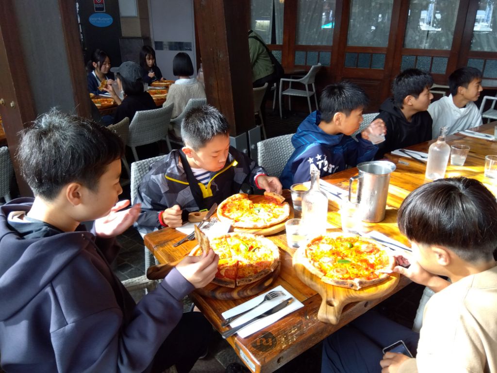 ピザ1枚ずつ食べる学生たちの写真